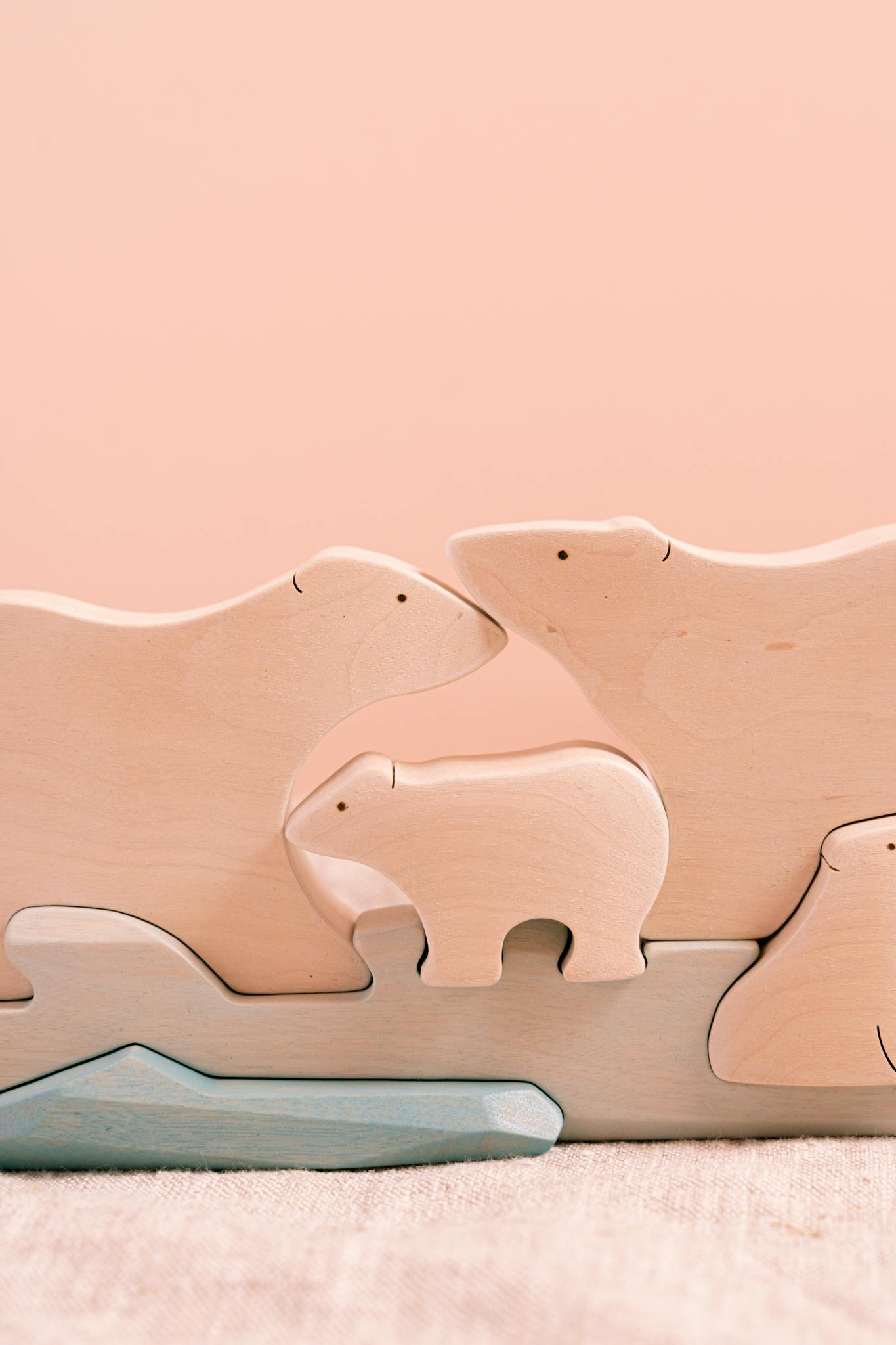 Minimalist wooden polar bear figurines arranged artistically against a peach background, ideal for decor.